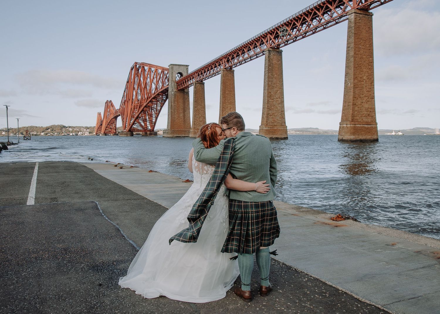 Wedding photos by iconic Forth Bridge in Scotland with dramatic coastal view.