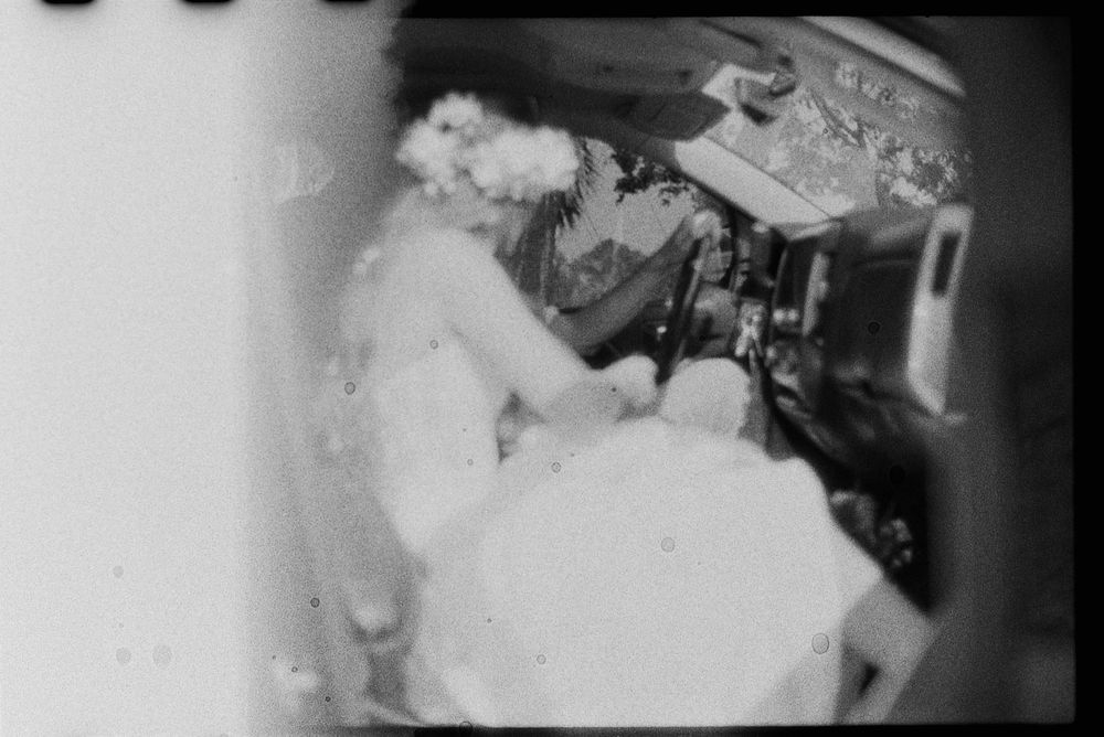 Vintage black and white photo of a bride in wedding dress sitting in an airplane cockpit.
