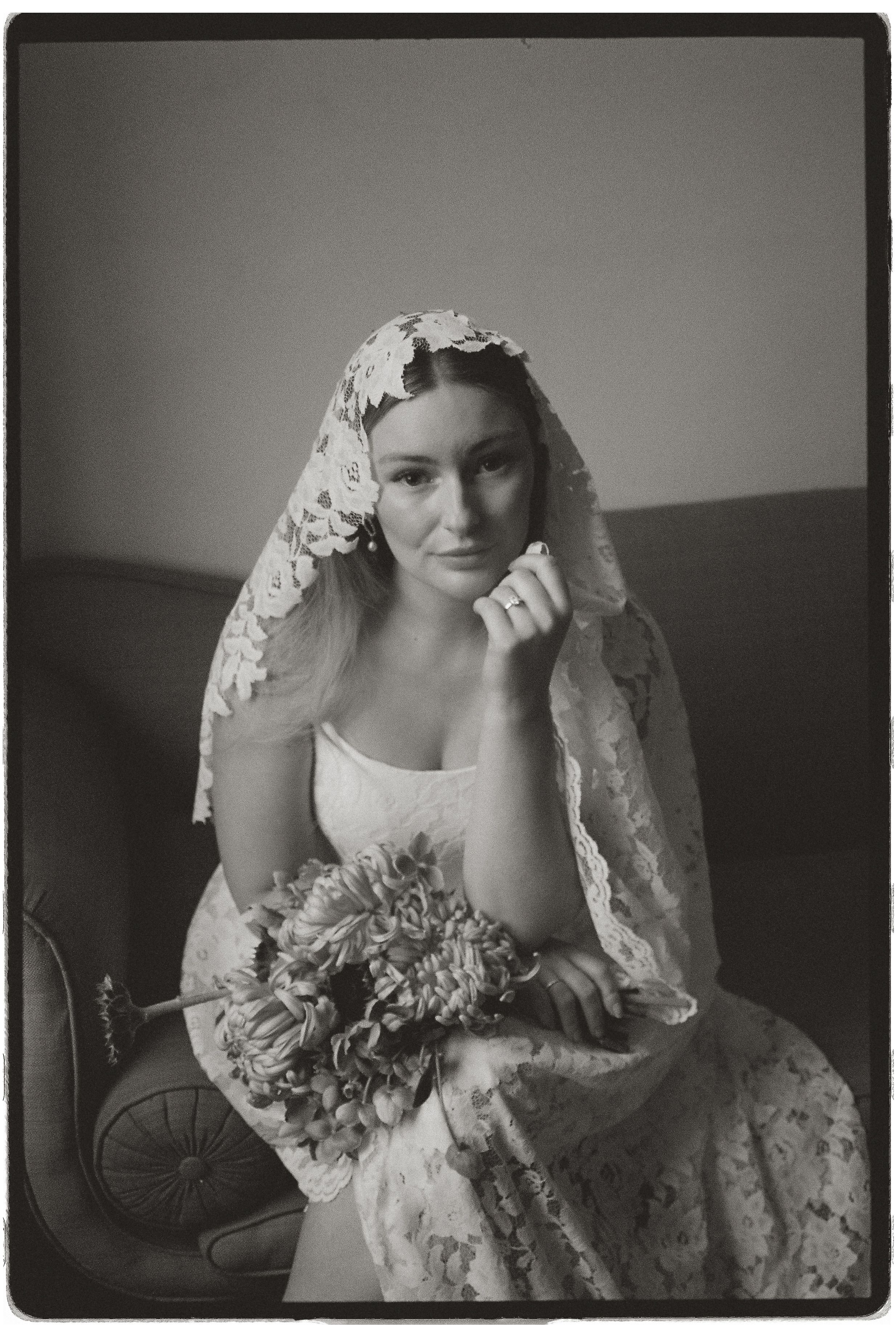 A vintage-style black and white photo series showing someone in an ornate lace wedding dress and veil in different poses.