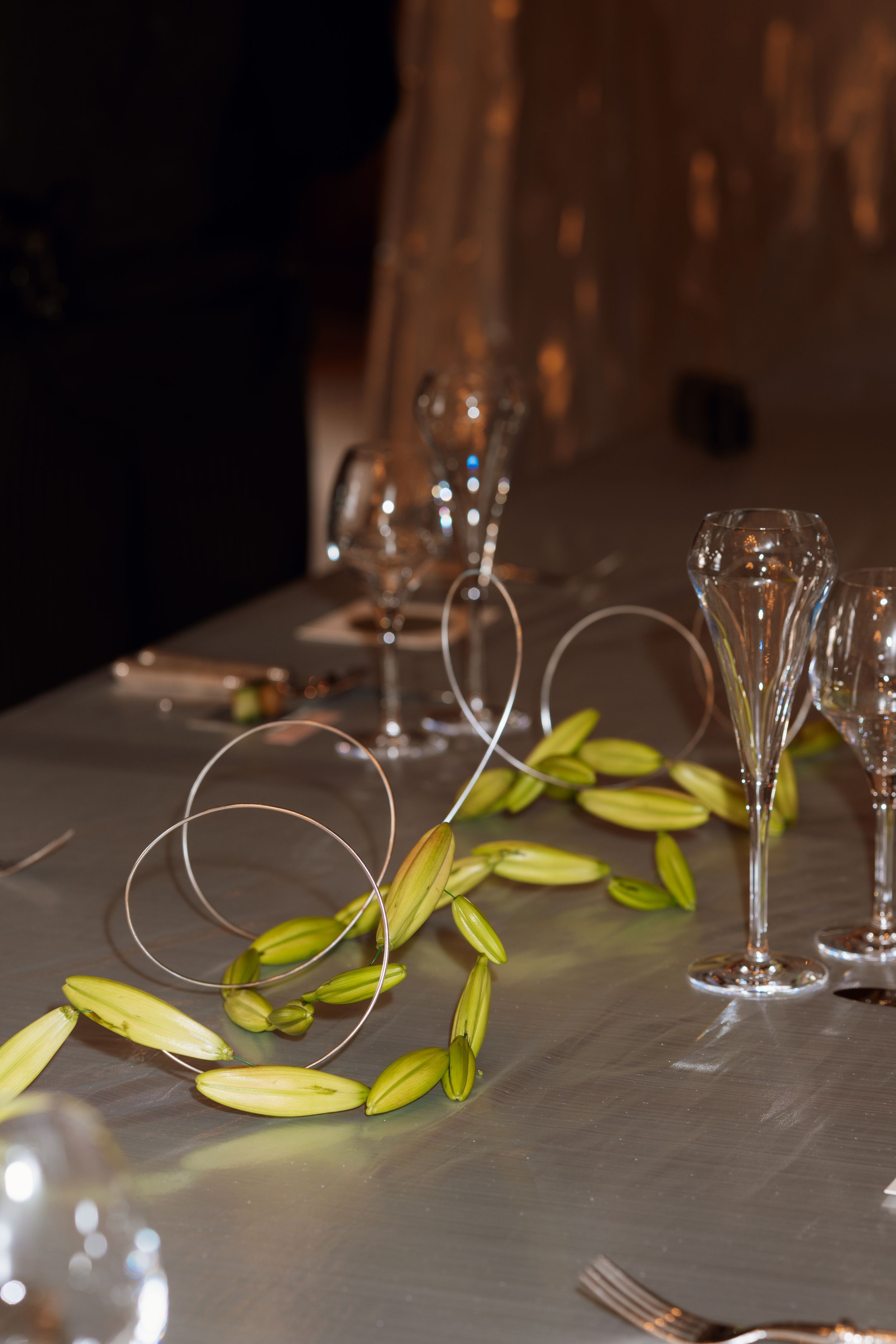 Empty wine glasses and yellow ribbons arranged on a gray tablecloth in a dimly lit restaurant setting.