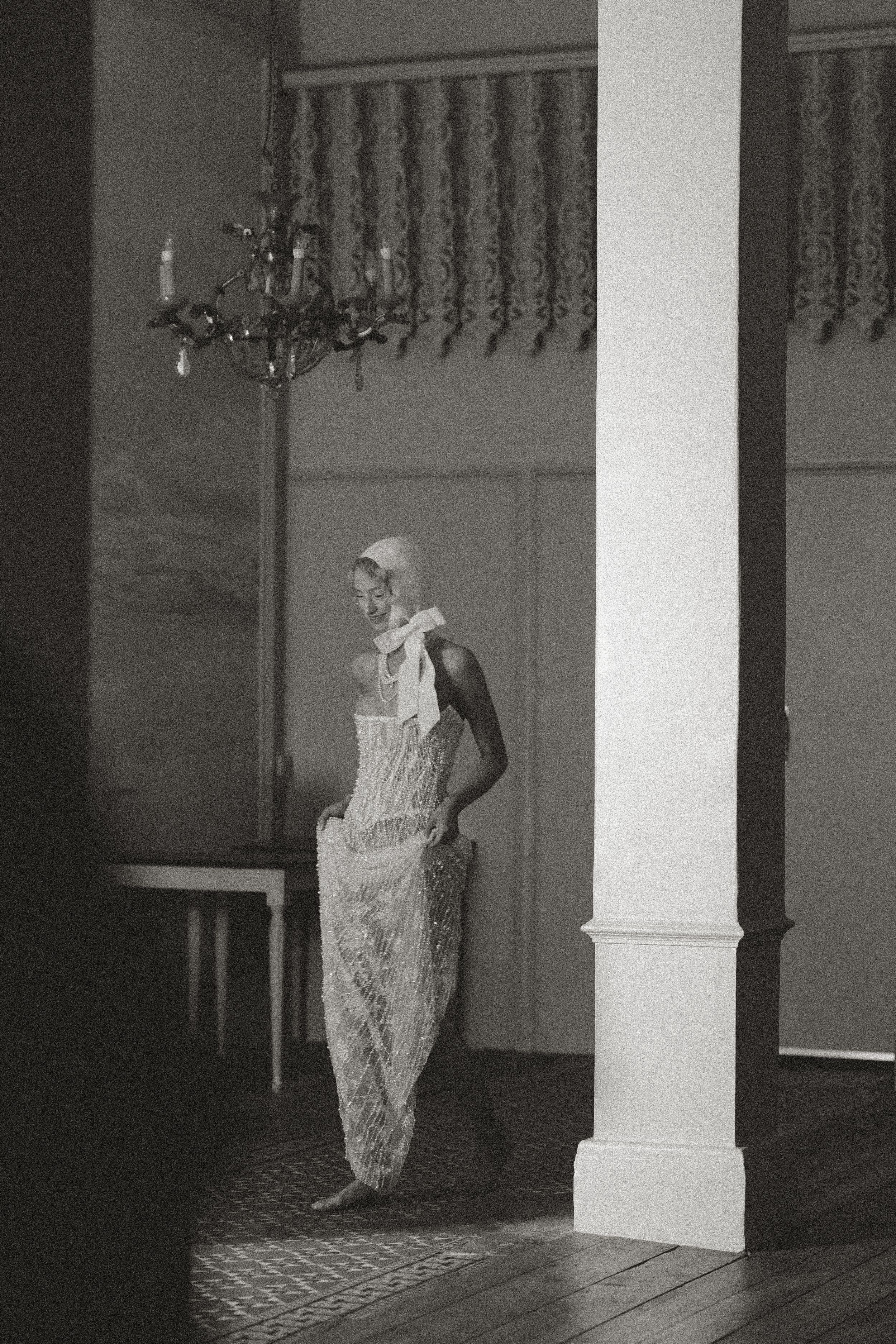 A series of black and white photographs showing ghostly figures in flowing white fabric standing in a dimly lit hallway.