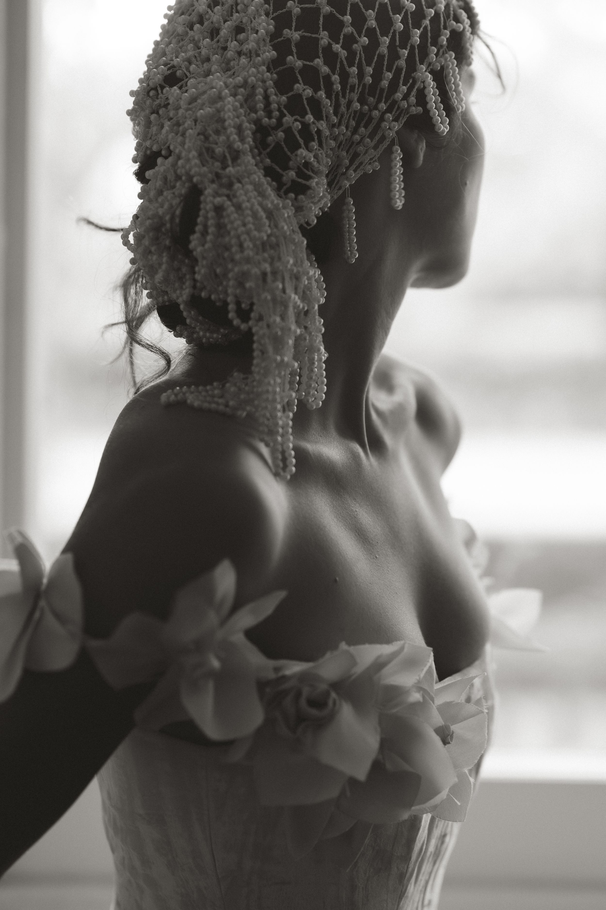 A vintage-style black and white photograph shows a delicate lace veil and floral details on formal attire.