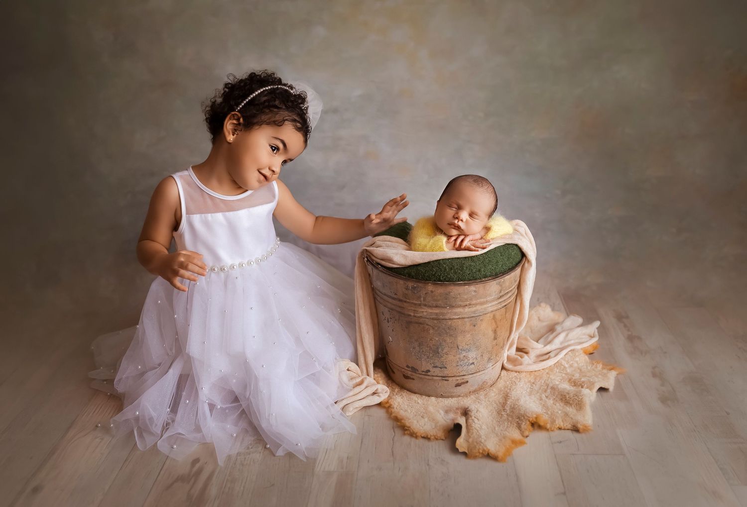 newborn baby in a bucket and big sister with white dress