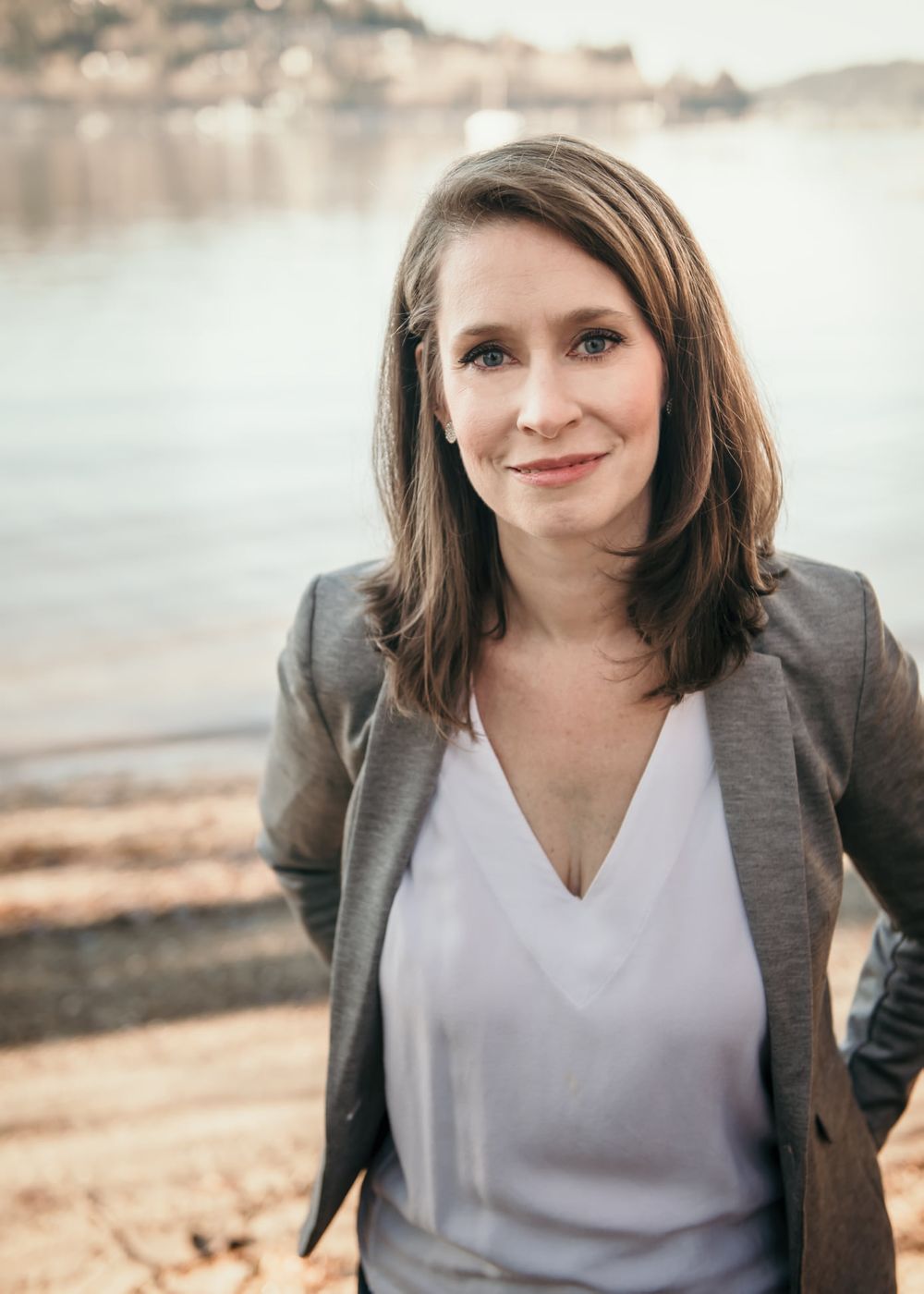 Professional headshot of a woman in a gray blazer and white top against a soft blurred background.