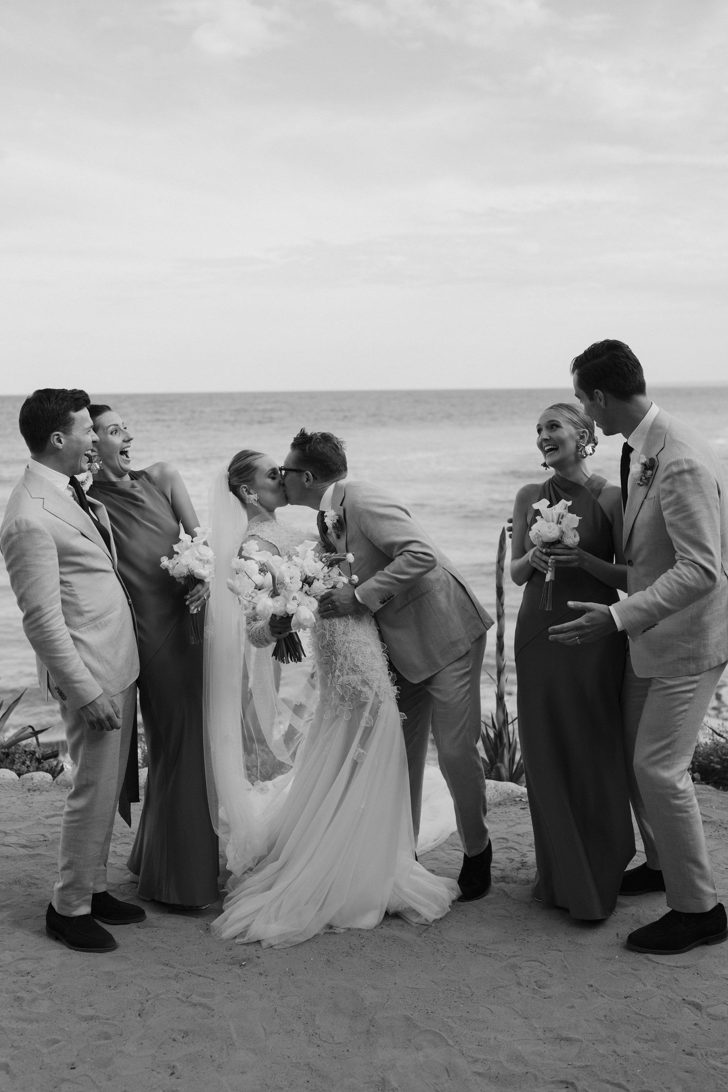 bride and groom kissing as bridal party laugh at amante ibiza