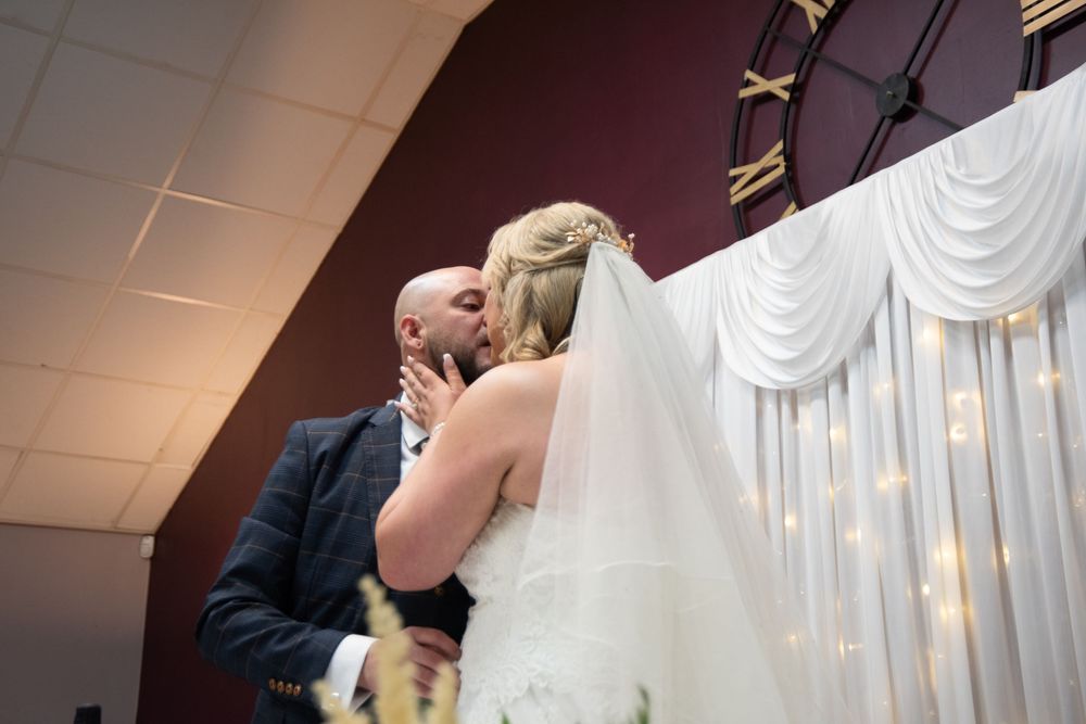 Wedding ceremony moments captured in front of elegant white draped backdrop with lighting.