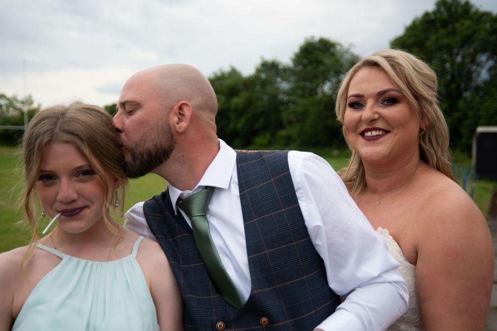 Wedding couple shares romantic moments outdoors with green scenery in the background.