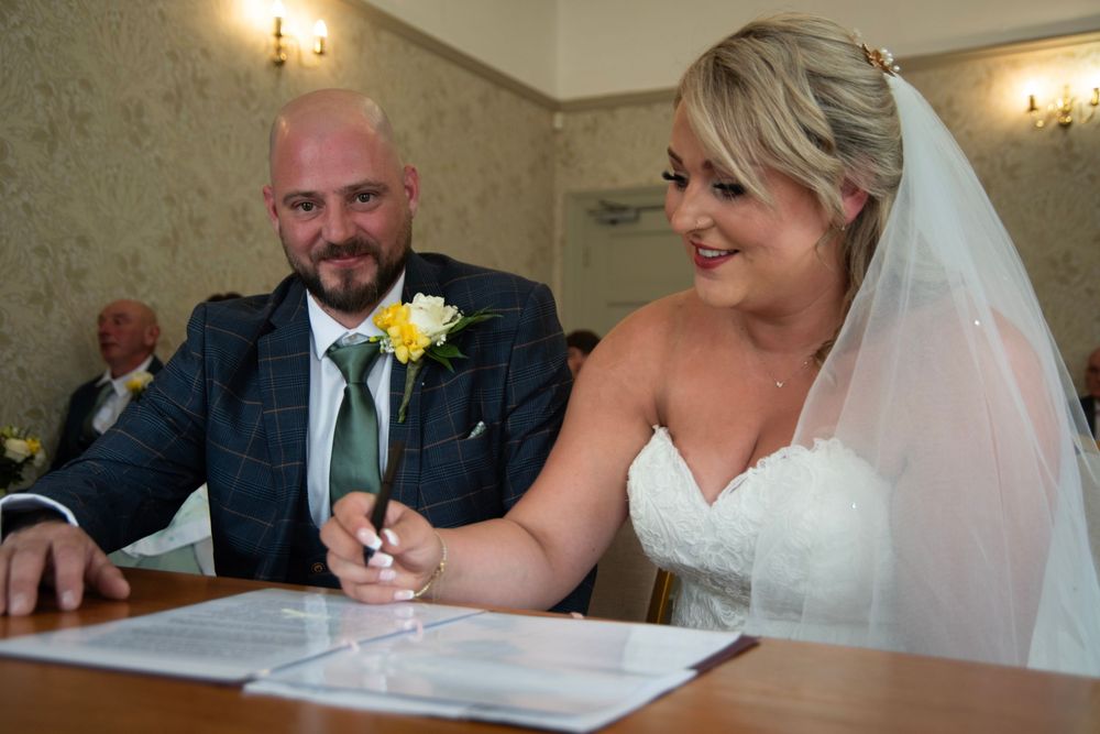 Candid moments of a wedding couple signing documents during their marriage ceremony.