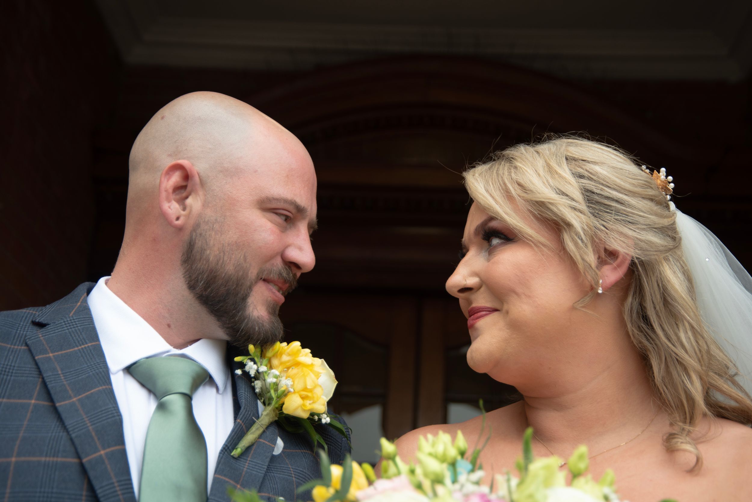 A couple shares an intimate moment together on their wedding day with yellow flowers and a mint green tie.