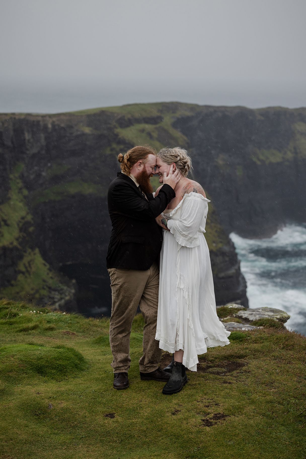 Bride and groom standing beneath dramatic storm clouds at Hags Head during Ireland elopement