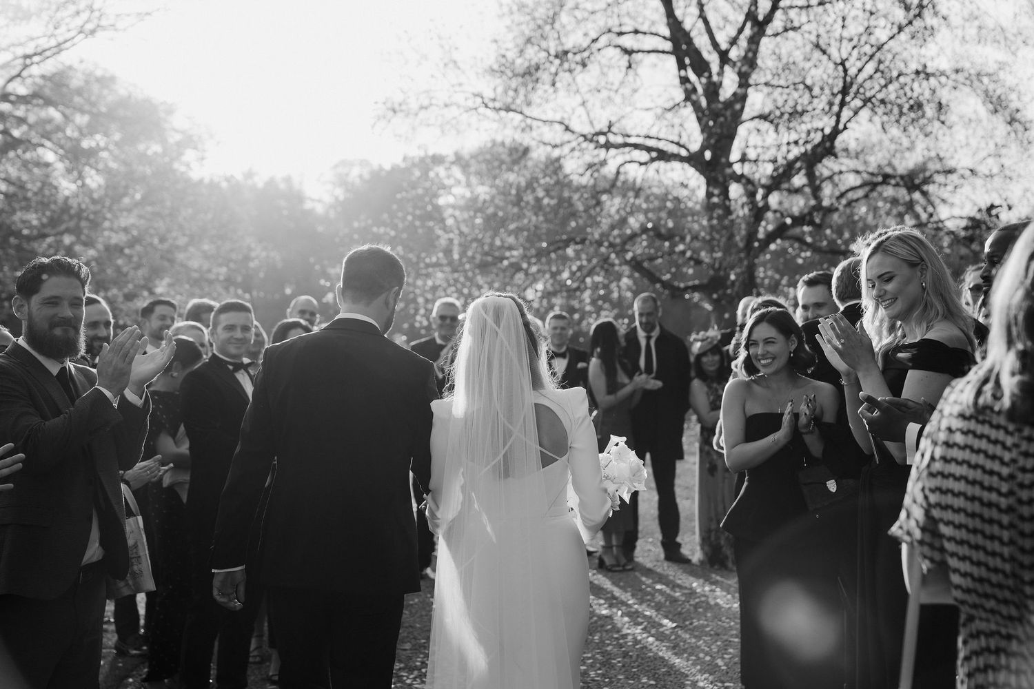 wedding guests clapping and cheering as the bride and groom pass them at Iscoyd park