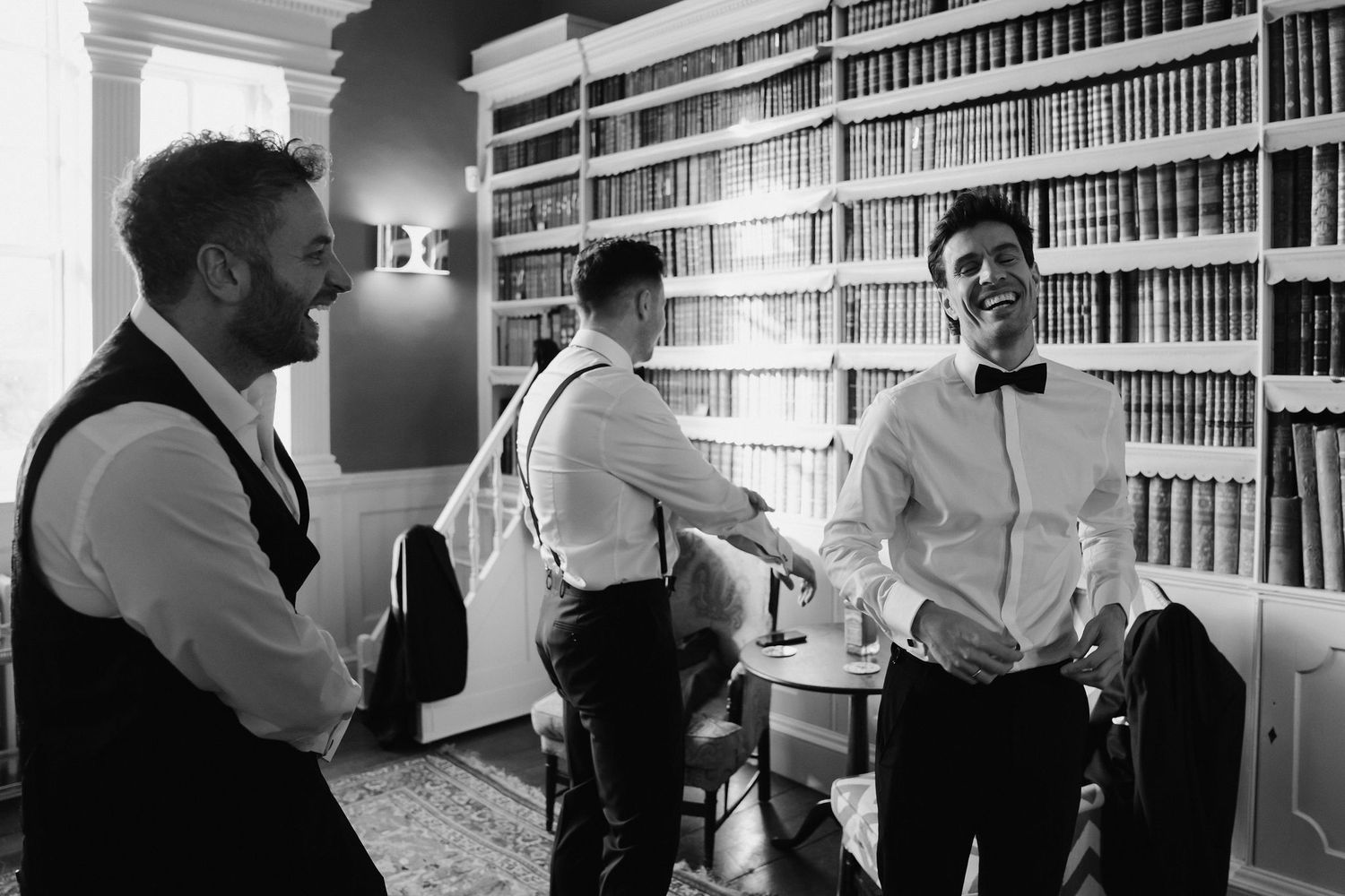 groomsmen getting ready and laughing in the library at Iscoyd park