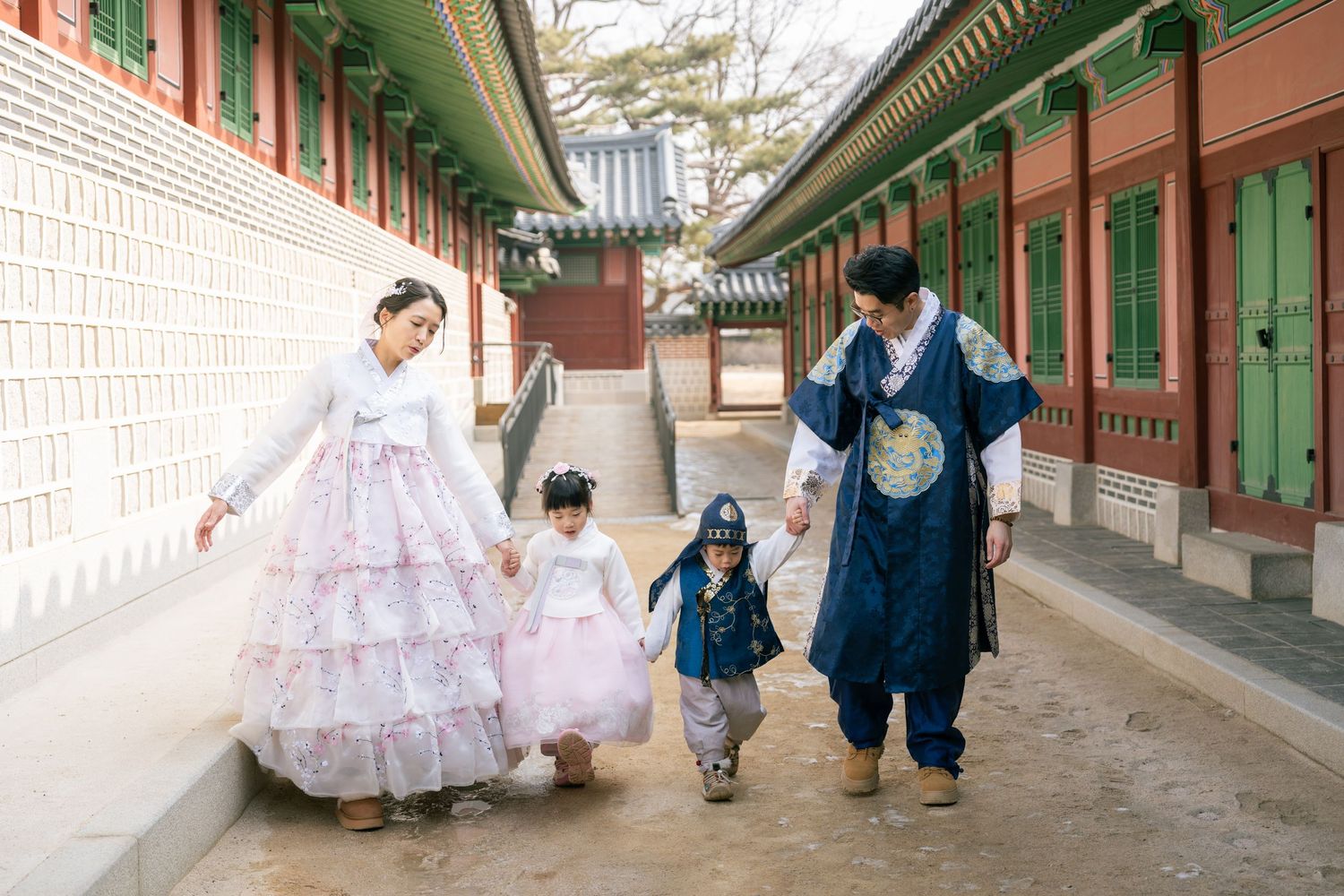Traditional Korean hanbok dresses and outfits are displayed in a historic wooden corridor with green painted details.
