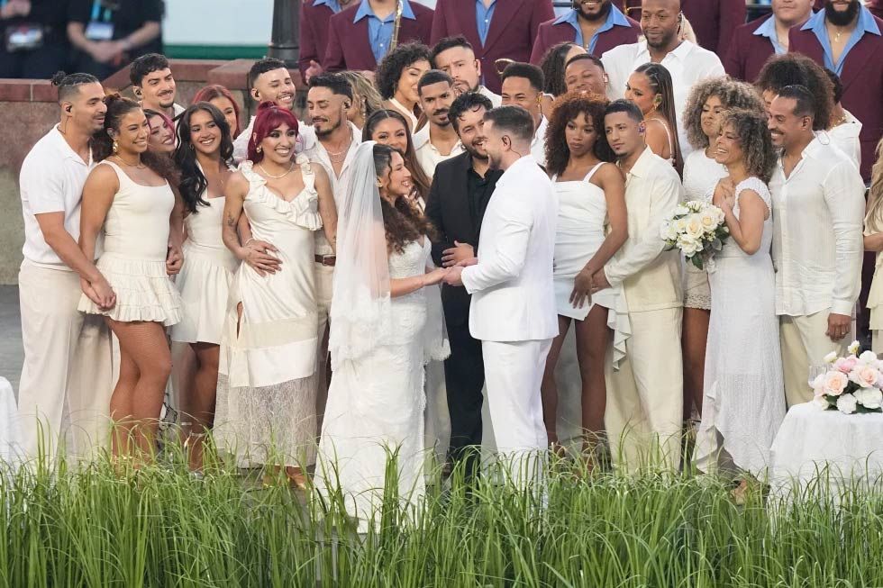 Excited Super Bowl performers celebrate a young couple getting married during the halftime show, cheering and embracing with joy.