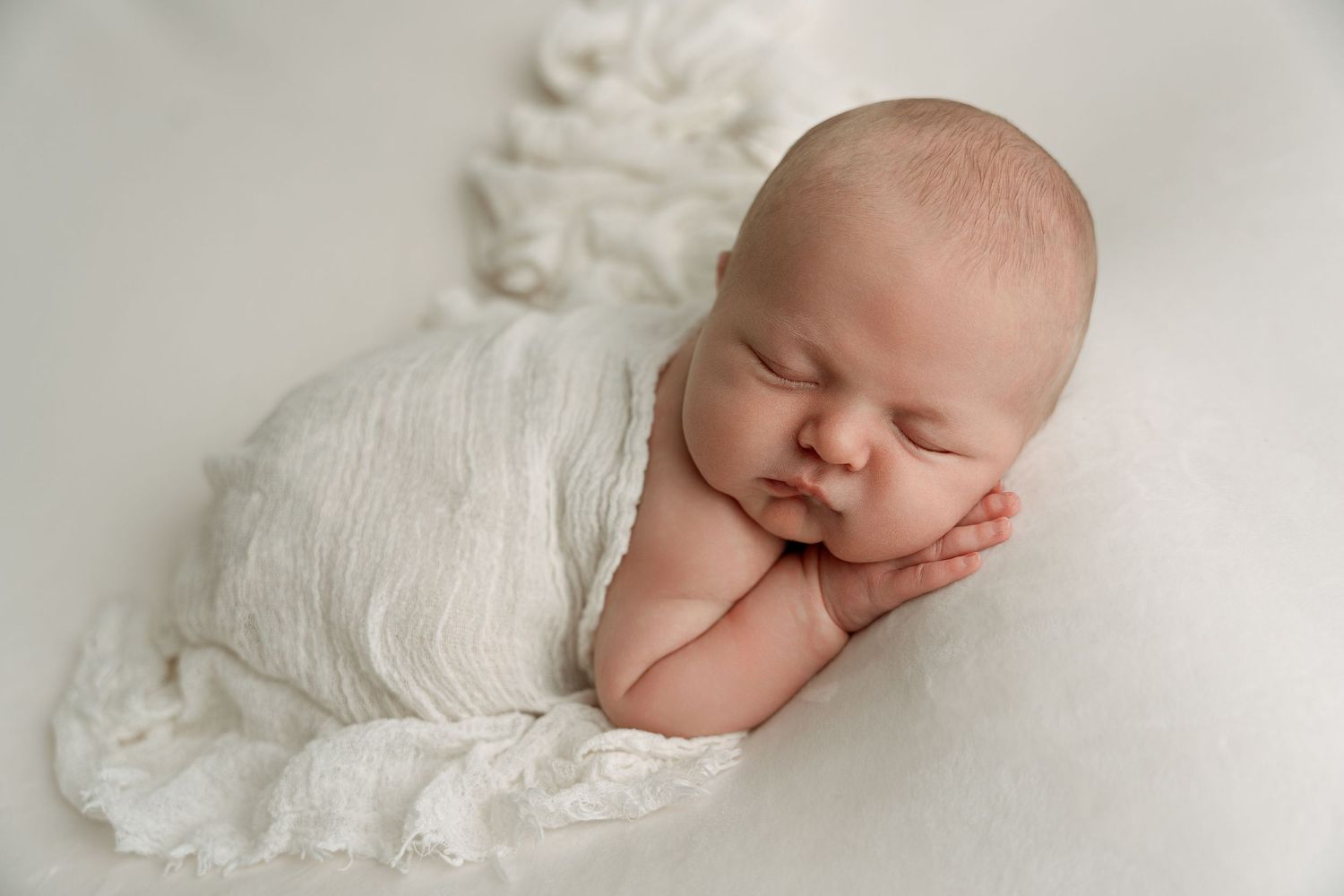 Newborn baby sleeping peacefully in heart-shaped wooden bowl lined with soft cream-colored blanket. – newborn photographer Paloma Schell