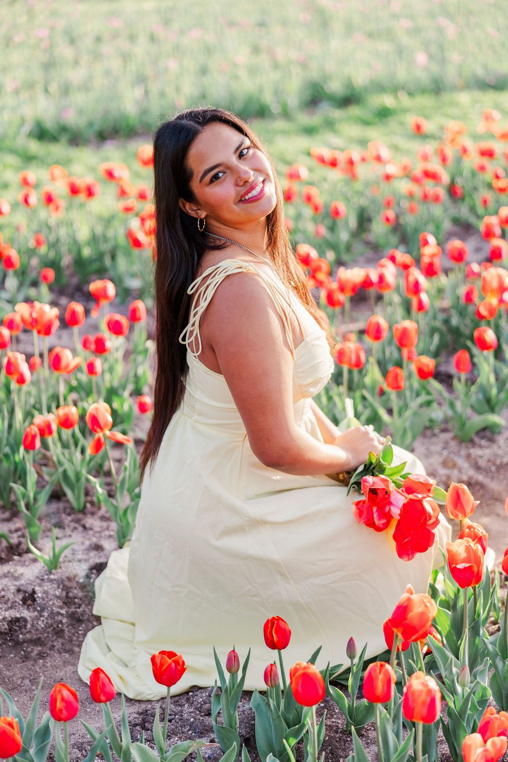 A yellow sundress twirls among bright red tulips in a garden during golden hour.