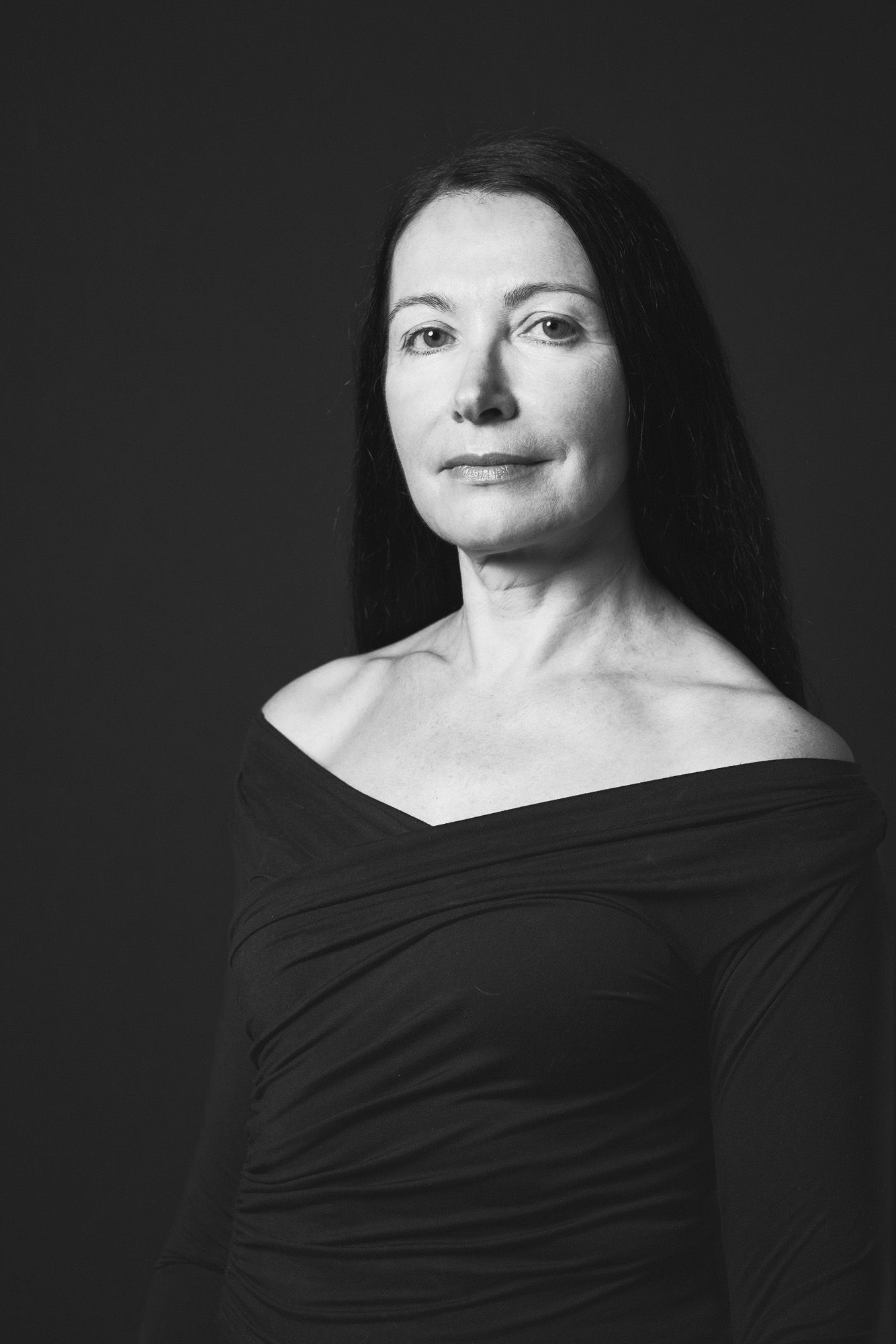 Timeless black and white portrait of a woman in a black off-shoulder top taken in a studio in King's Lynn, Norfolk