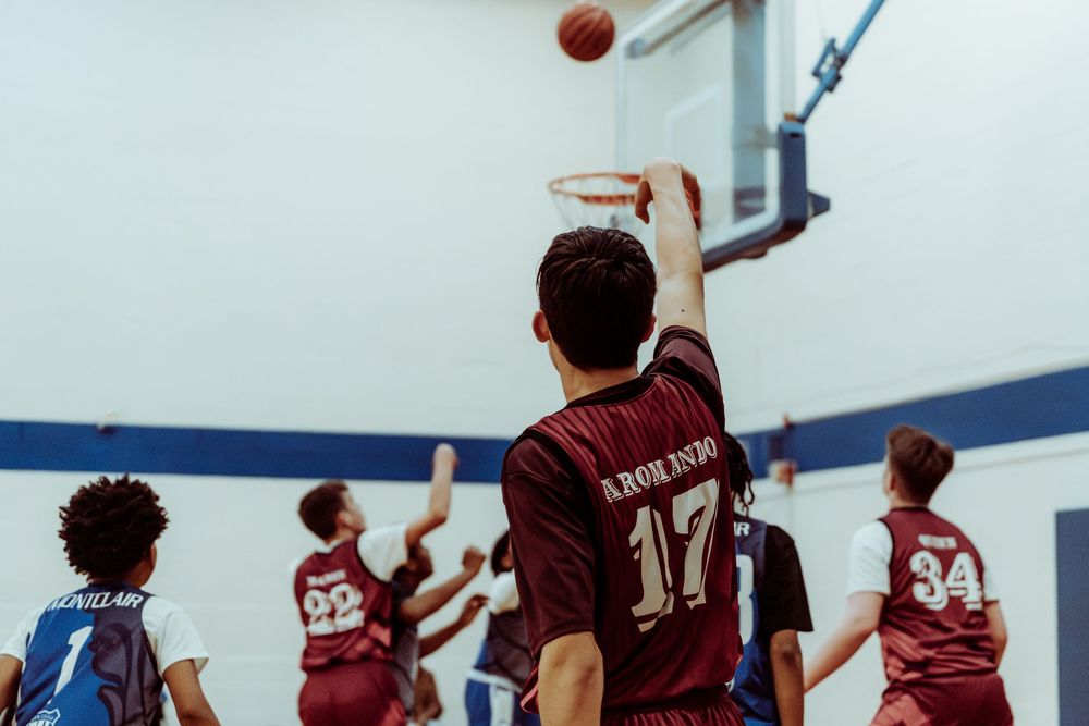 A basketball player in a maroon number 17 jersey shoots toward the hoop during a game.