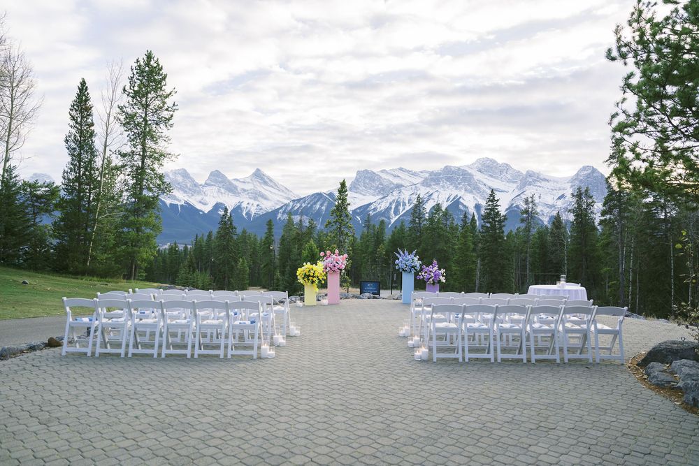 White chairs arranged for an outdoor mountain wedding ceremony with snow-capped peaks in the background.