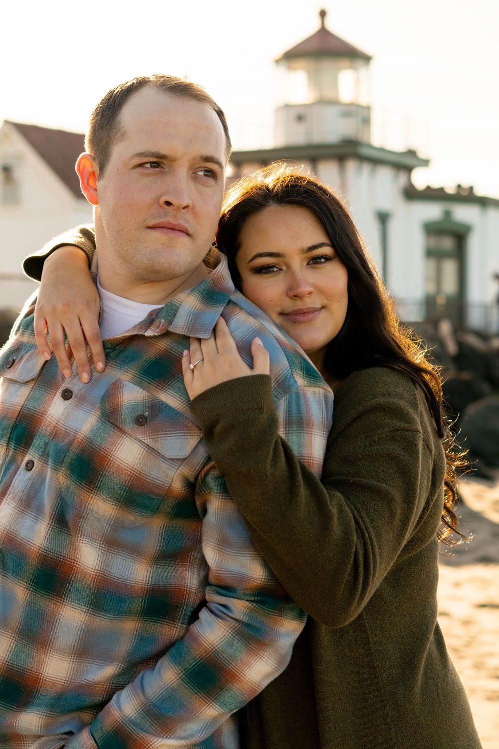 A couple embraces tenderly during a golden hour photoshoot with warm sunlight creating a romantic atmosphere.