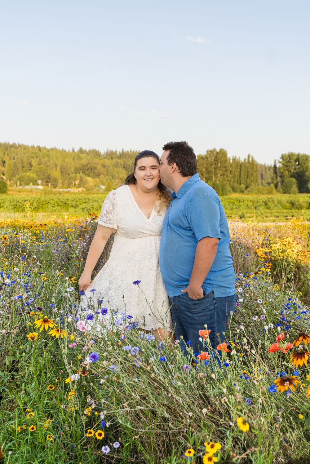 A couple shares an intimate moment among vibrant wildflowers in a sunny meadow during golden hour.