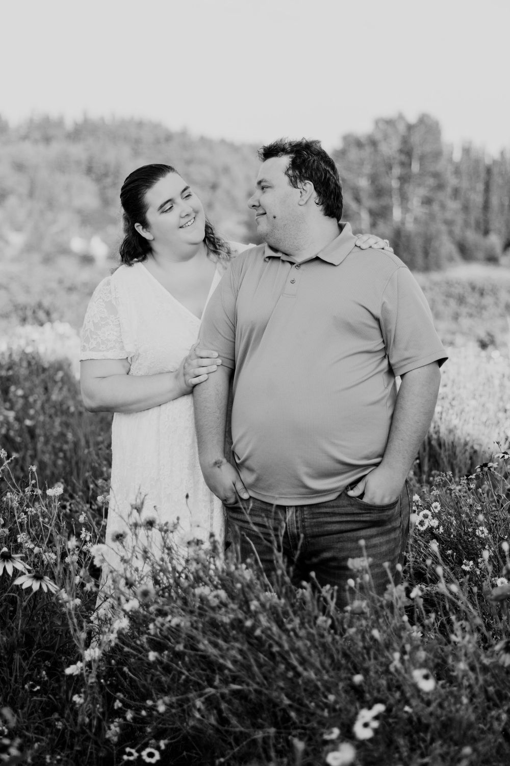 A couple shares intimate moments in a wildflower field during a black and white outdoor photo session.