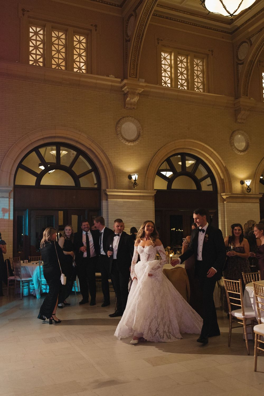 Elegant ballroom with arched windows and ornate details hosting a formal event.