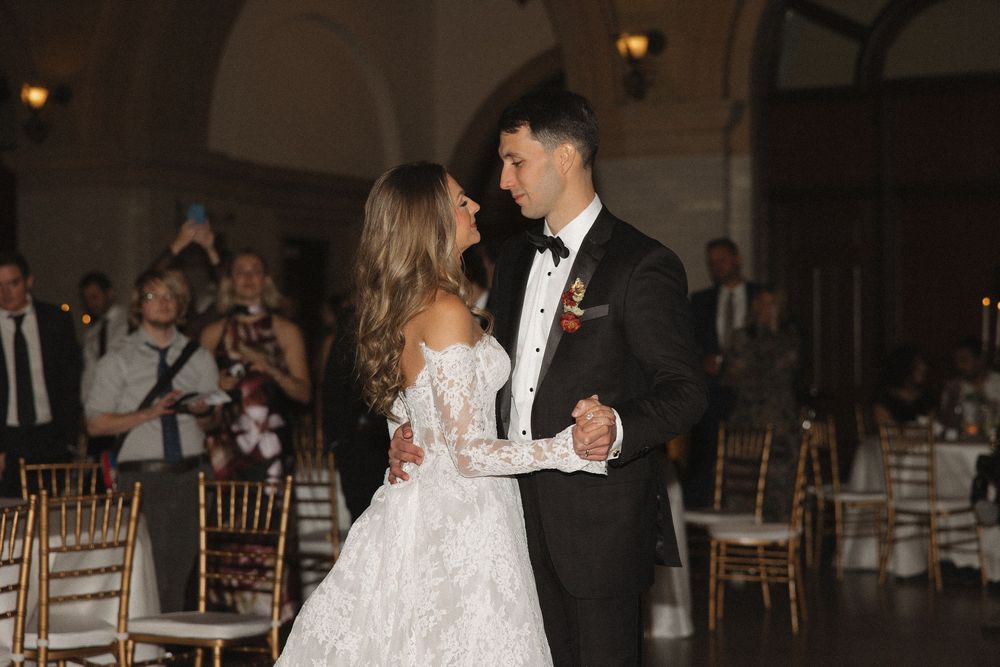 A couple shares a romantic dance at their wedding reception in an elegant ballroom setting.