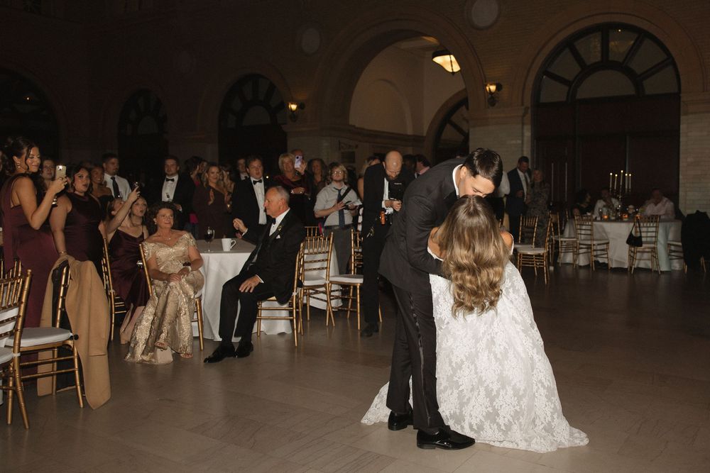Wedding reception venue with elegant lighting and guests dancing on the dance floor.