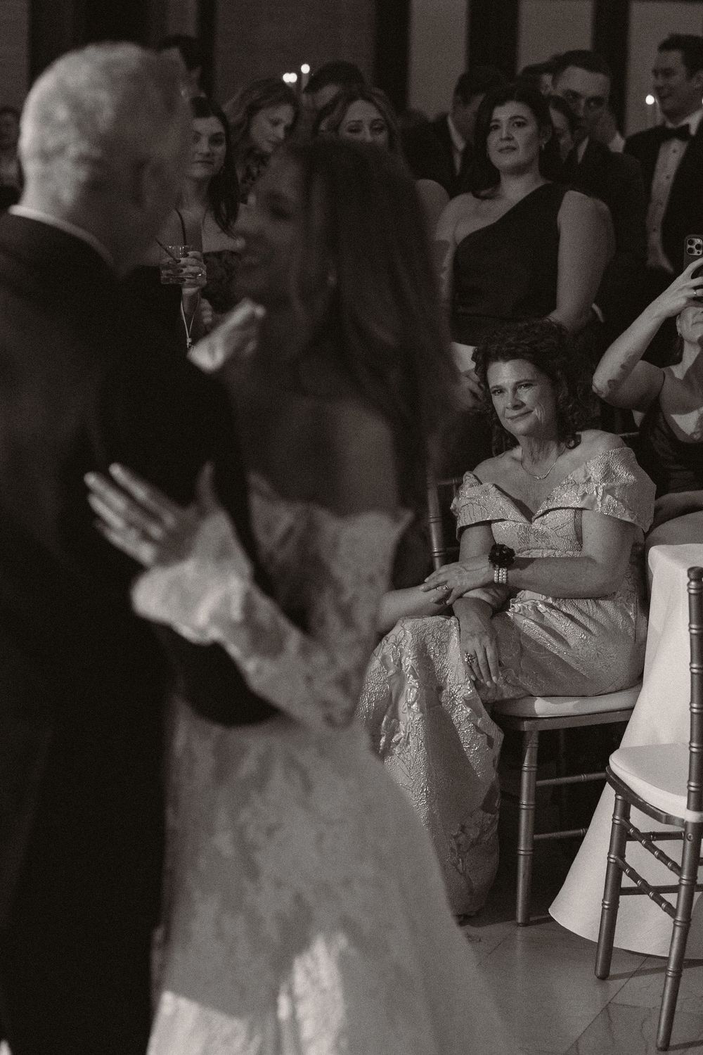 Wedding reception guests seated at tables in a dimly lit ballroom.