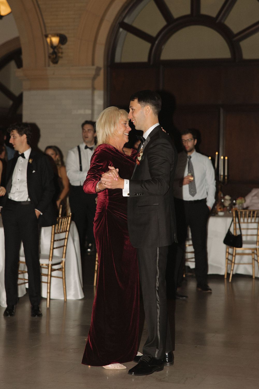 Wedding guests dance together on a ballroom floor during an elegant evening reception.