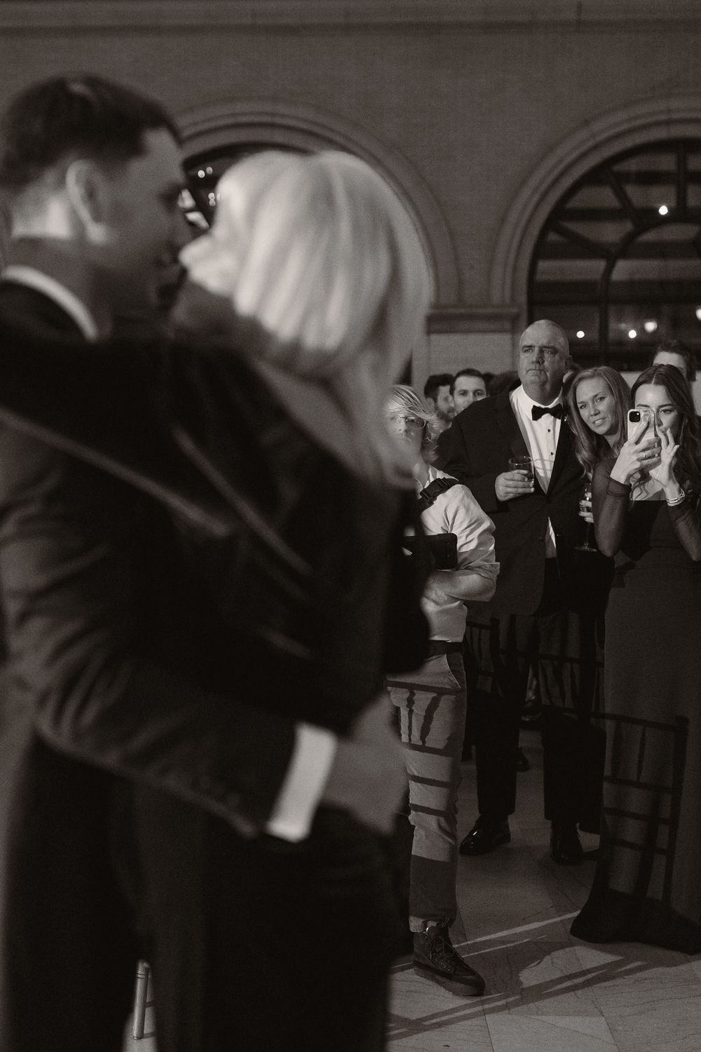 Wedding guests watching and taking photos during a celebration.