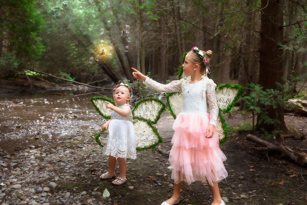 A magical forest scene with pink tulle and whimsical poses creates an enchanting outdoor photo session.