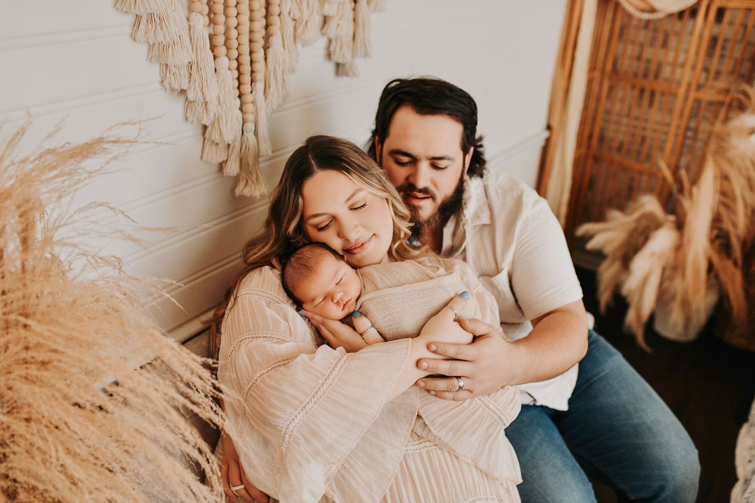 Parents standing together with their newborn in soft natural light