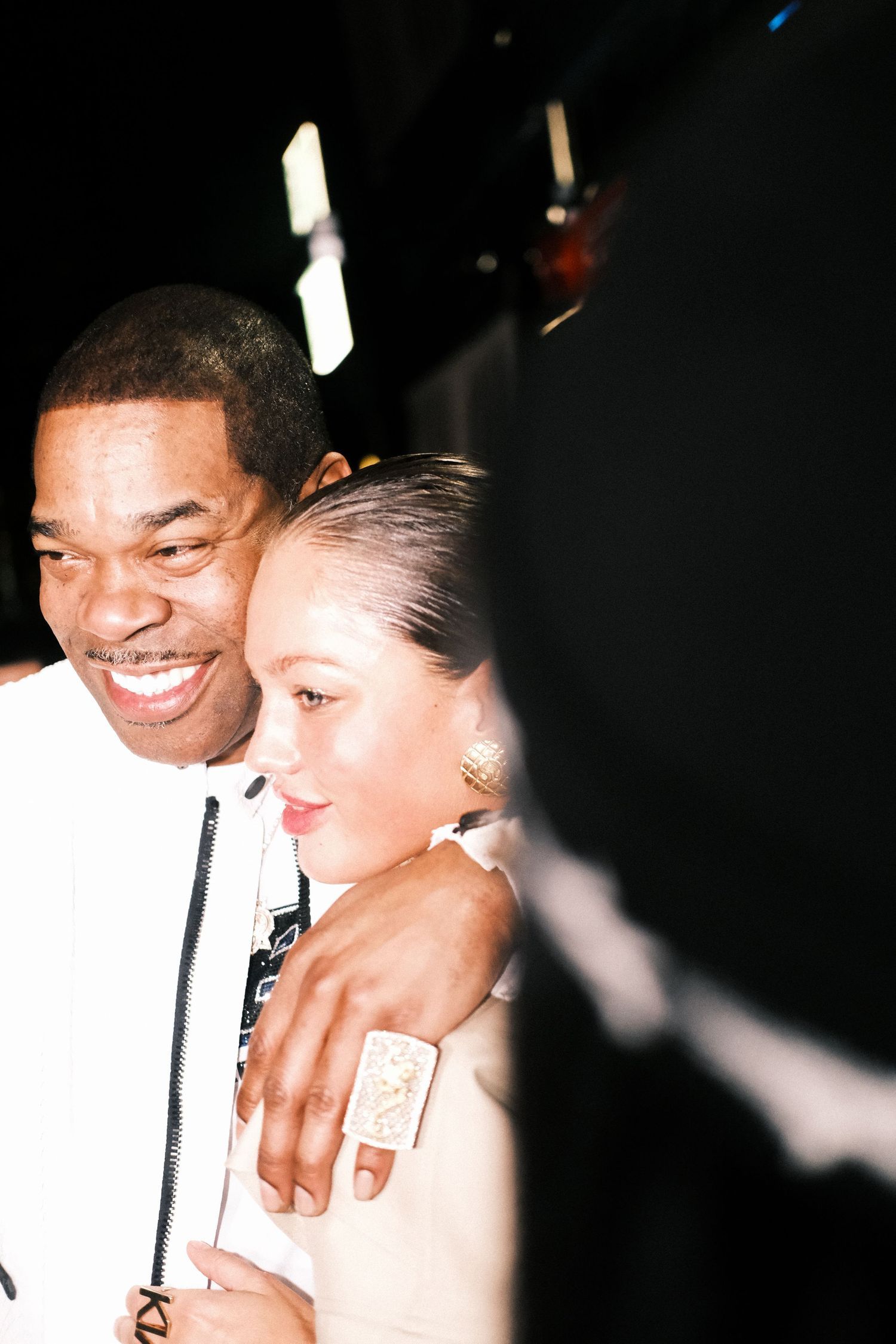 A couple shares a tender moment while holding drinks at a dimly lit party or nightclub.