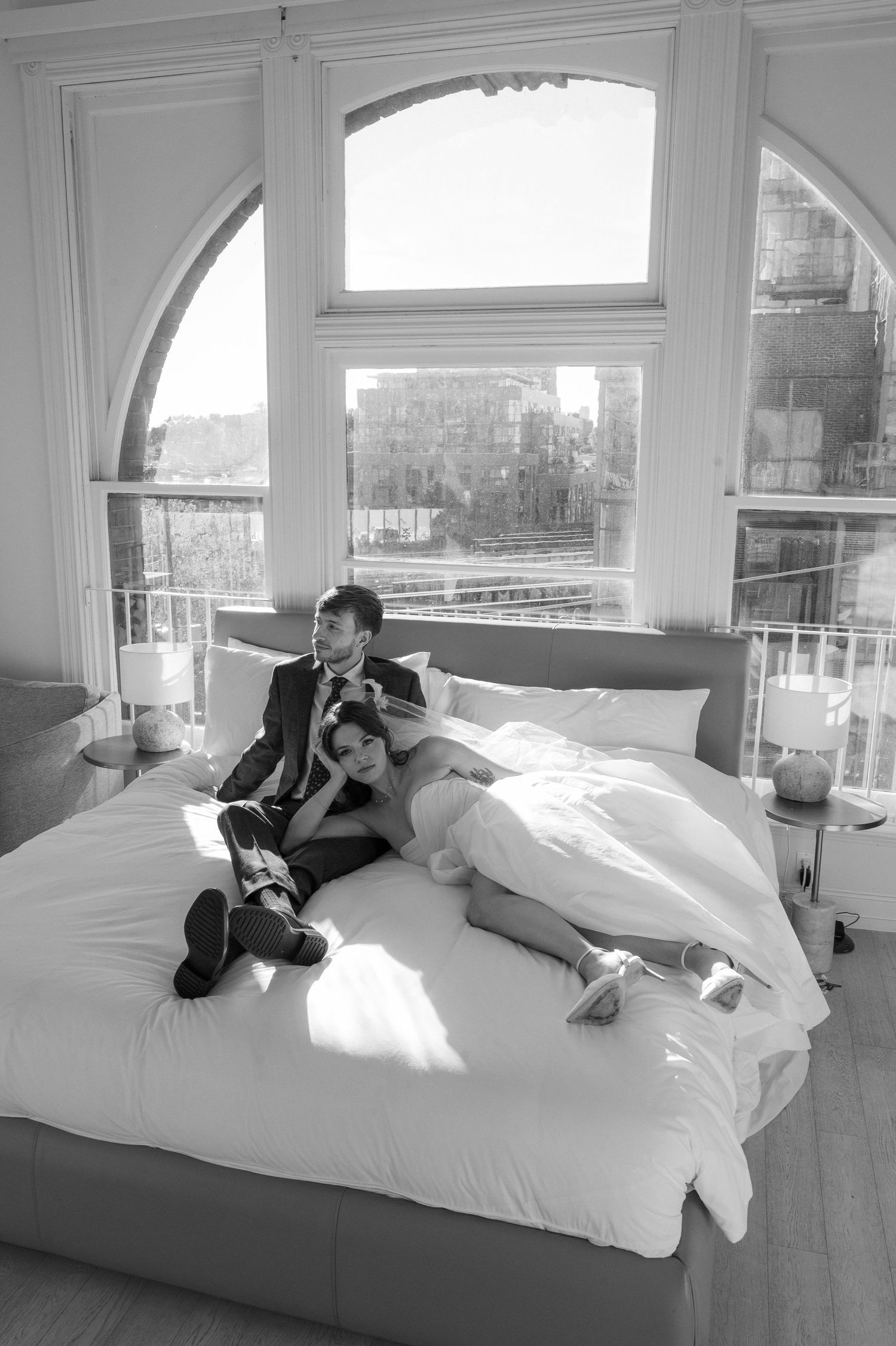 A series of black and white photos showing someone relaxing on a white bed in a bright sunlit room.