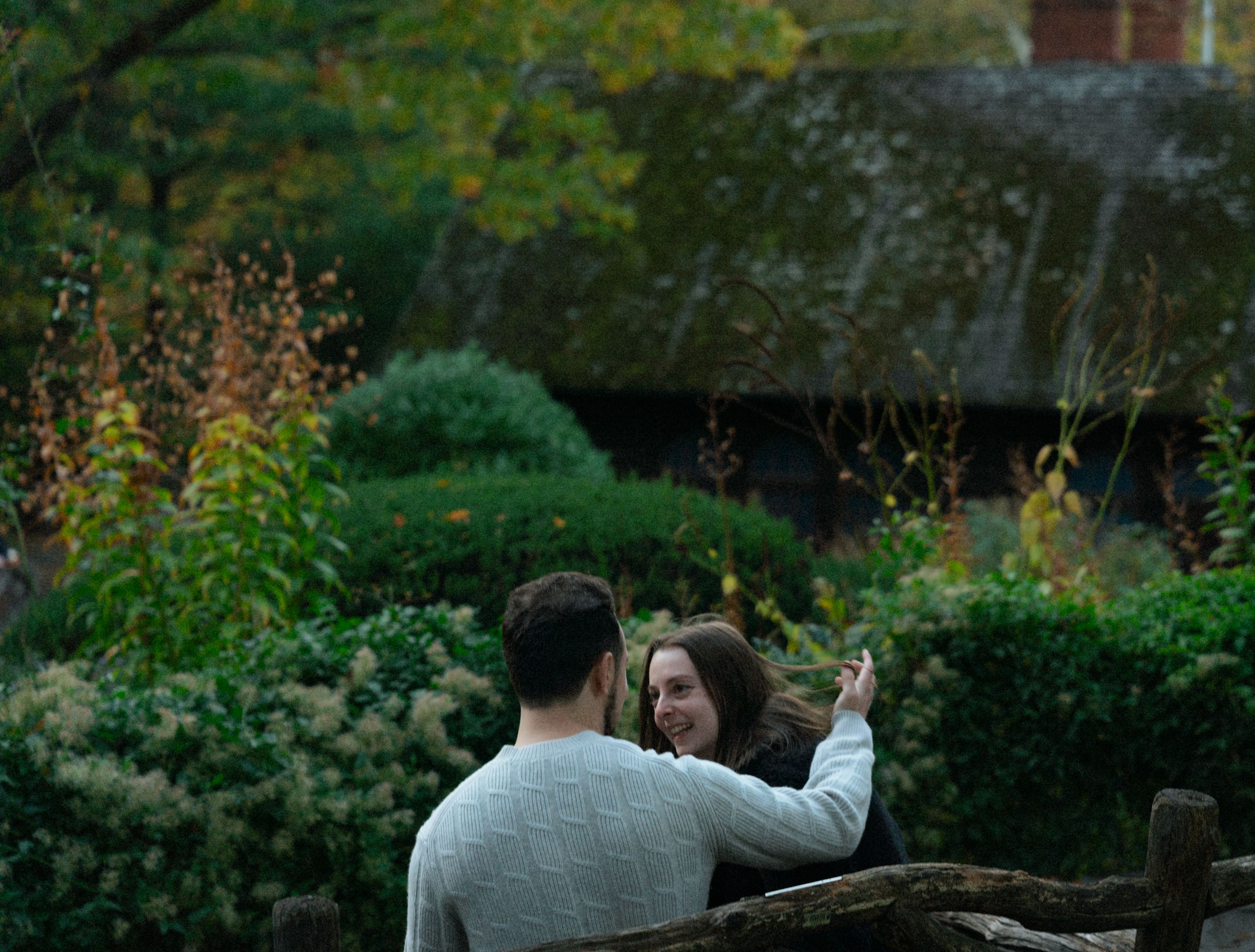 Couple sharing romantic moment in garden setting during golden hour.