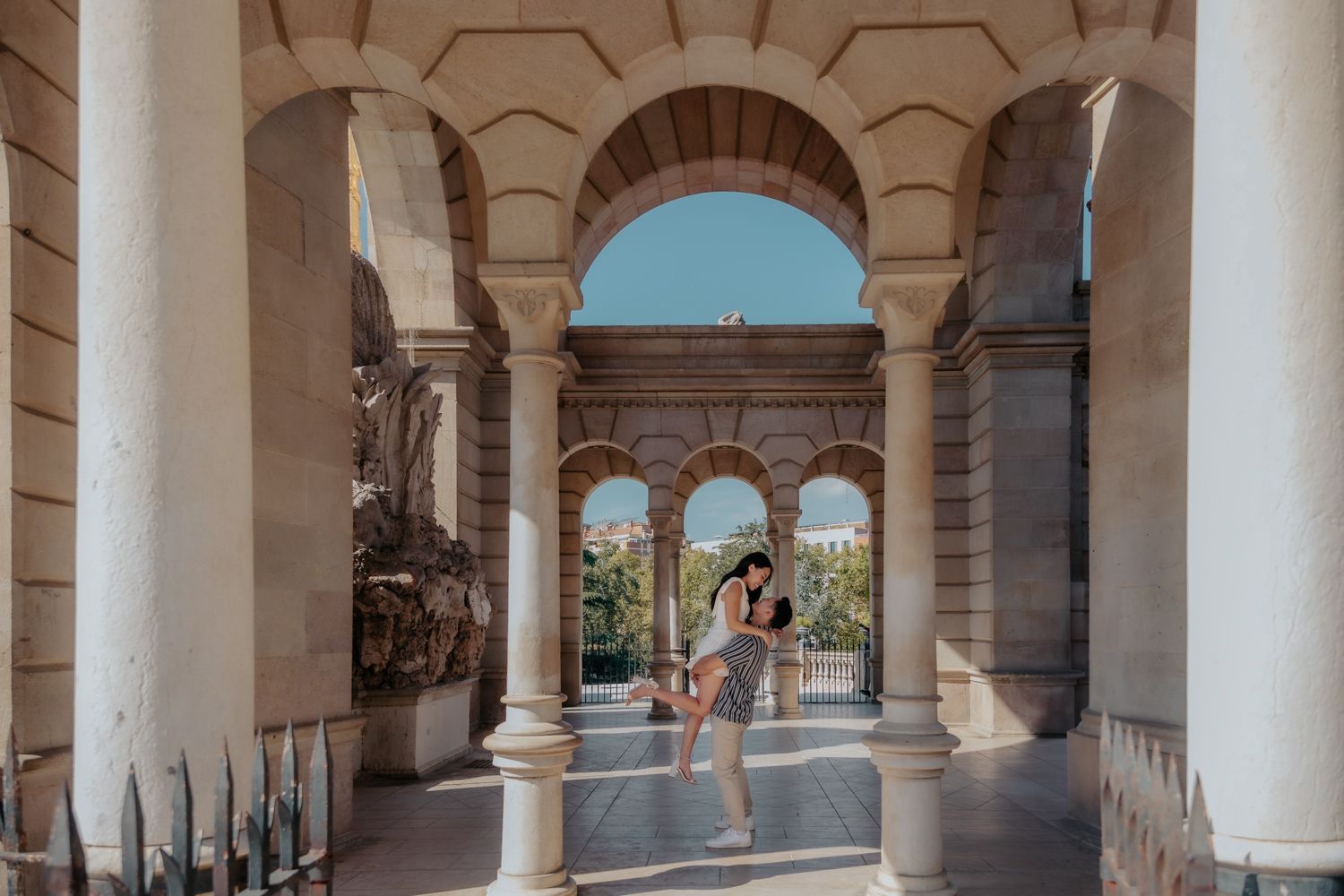Wide shot of couple holding hands with Sagrada Familia Nativity facade background.