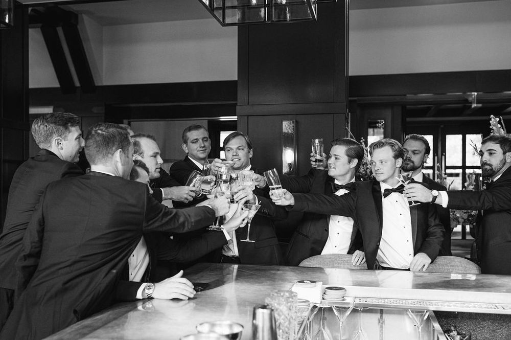A group of men in formal attire toasting and celebrating at a bar counter.