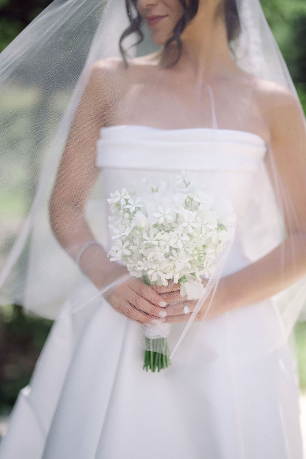 Close-up shots of a delicate white bridal bouquet with small flowers against a light background.