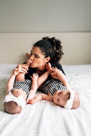 A series of tender moments between parent and newborn baby lying on white bedding in matching black and white gingham outfits.