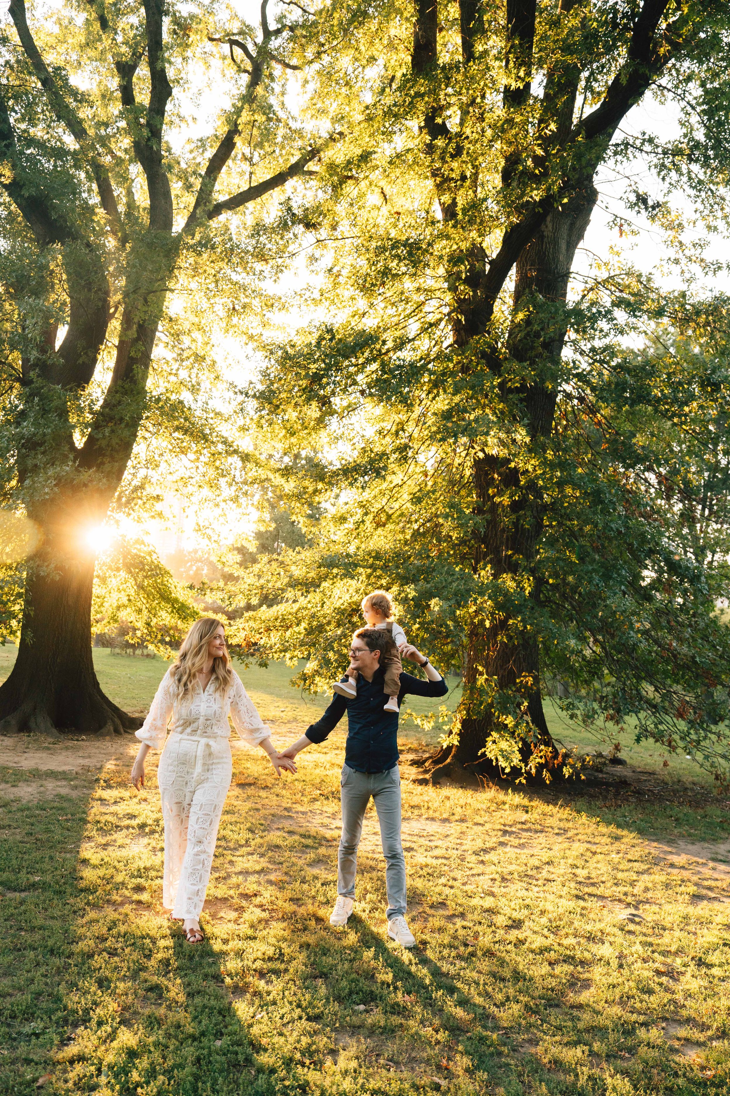 Two people dance together in a sunlit autumn park as golden sunbeams filter through the trees at sunset.