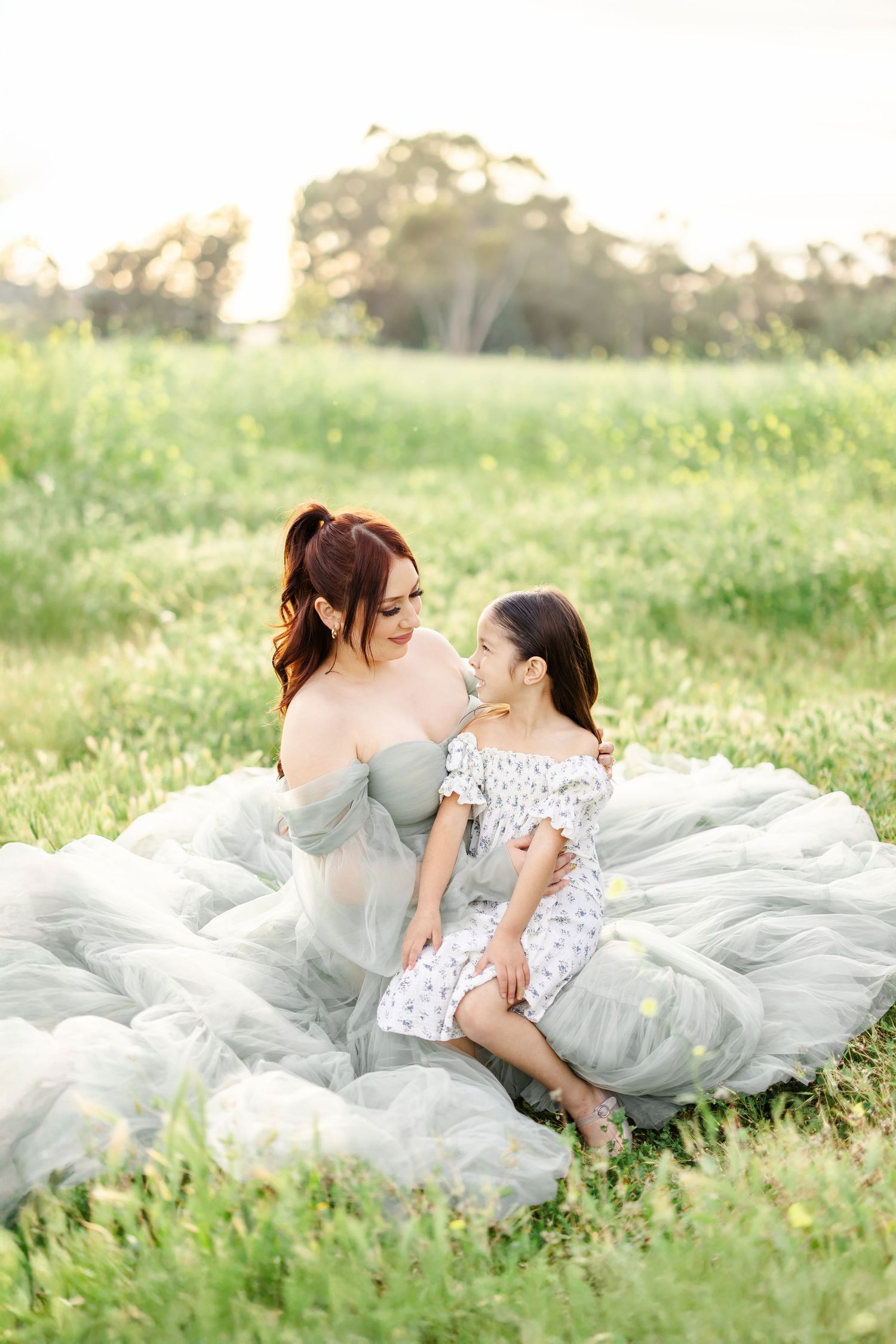 Romantic outdoor portrait session with flowing gowns amid wildflowers at sunset.
