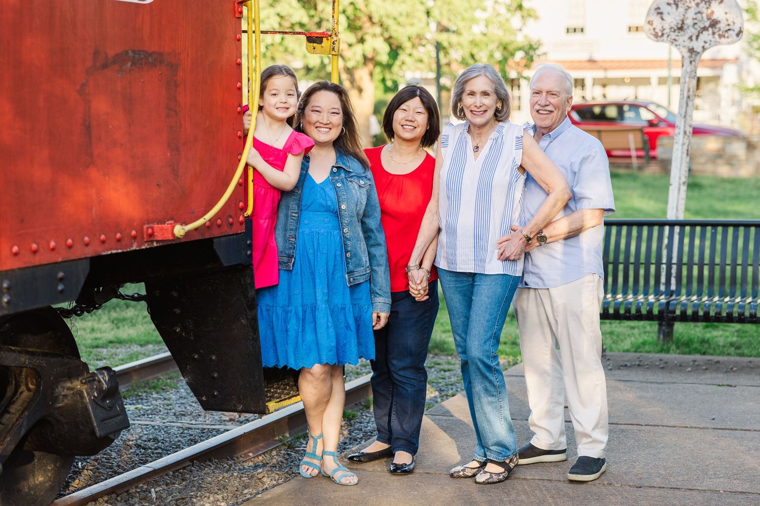 A group of people stand together outdoors wearing bright colors and casual clothing for a family photo.