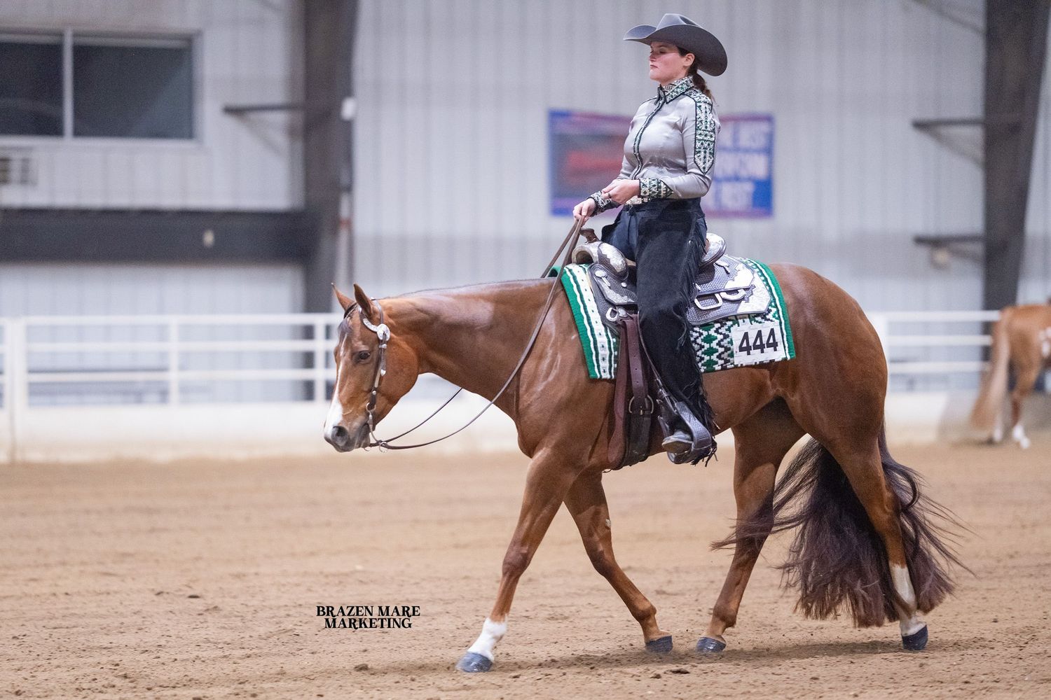 A rider performs in a western equestrian competition with American flags displayed in the background.