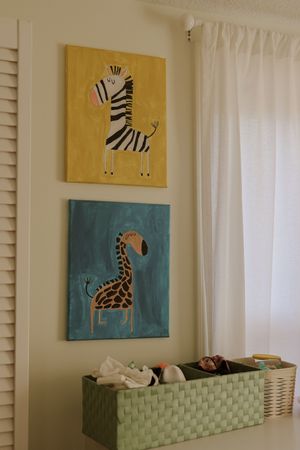 Nursery wall decorated with safari animal artwork in yellow and teal colors.