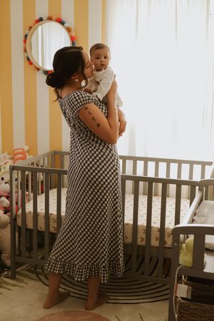 A series of tender moments between parent and baby in a nursery with striped walls.