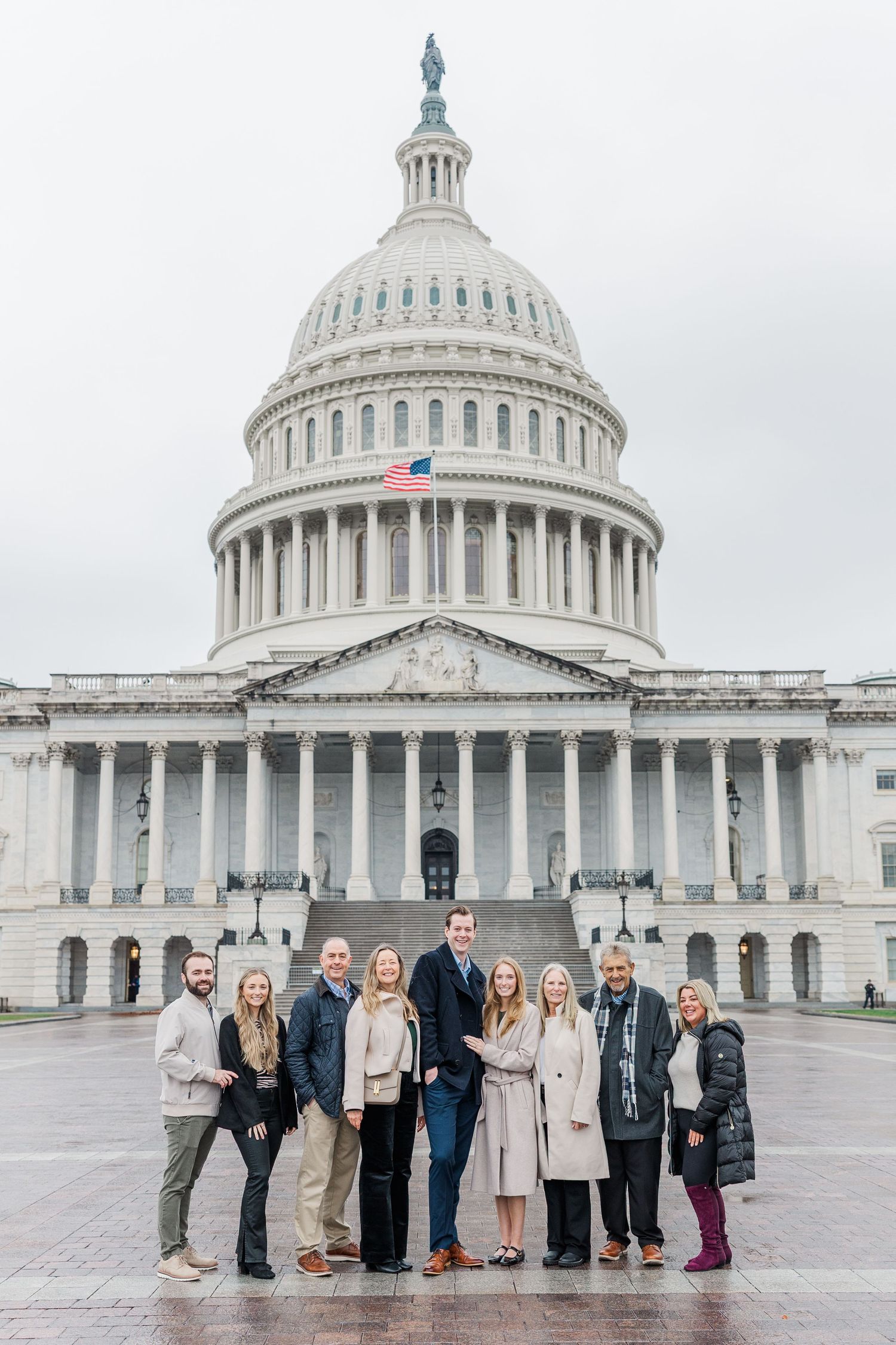 A group of people standing in front of the United States Capitol Building on an overcast day.