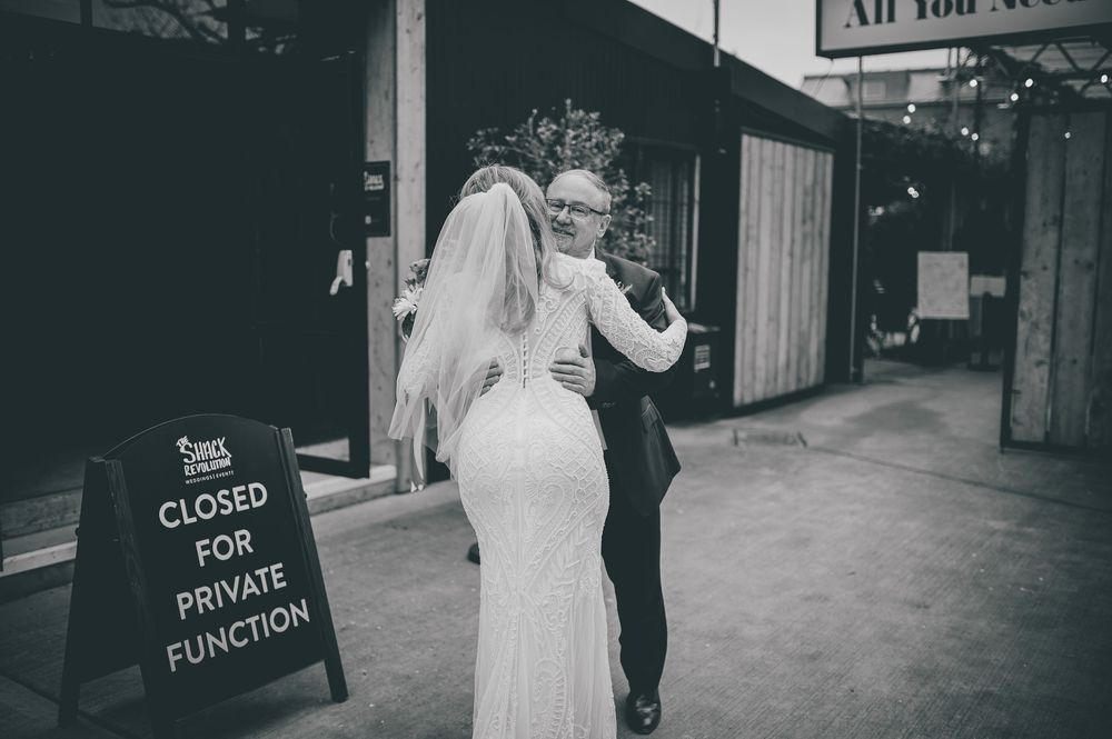 A black and white vintage photograph shows a bride and groom exiting a building while guests throw rice in celebration.