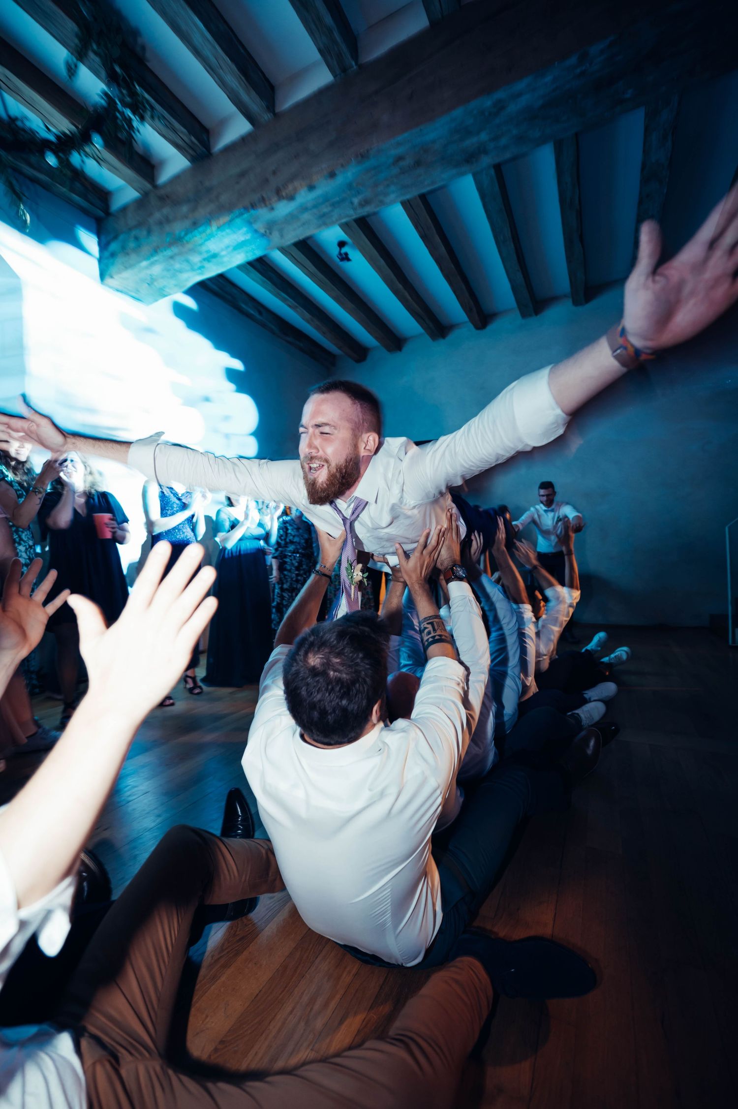 Invités portant un convive sur la piste de danse lors de la soirée de mariage en Bretagne.